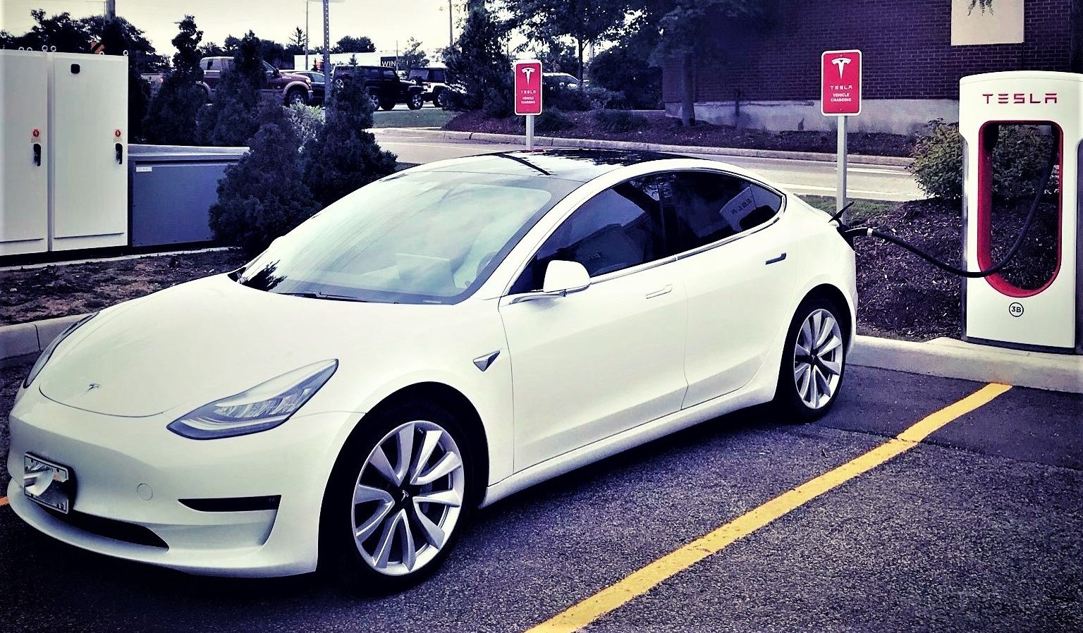 White Tesla Model 3 in Front of Super Charger